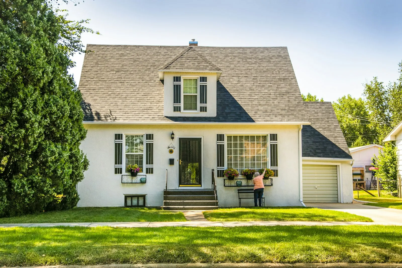 A white two-story house with a green lawn on a sunny day