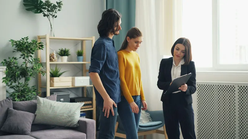 An agent with a clipboard showing a living room to a couple